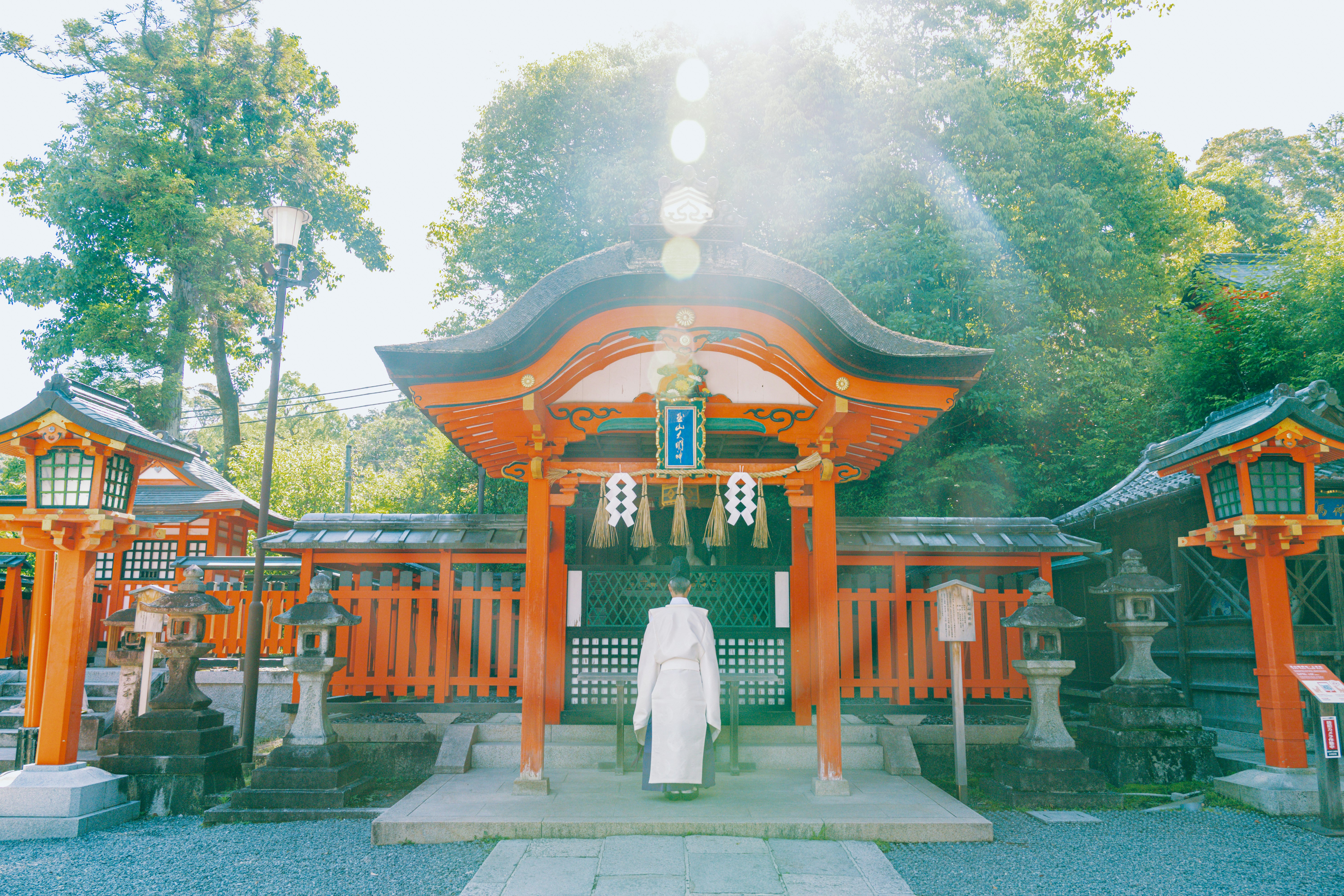 Orange Japanese architecture frame a man in a white robe.