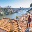 1063875272
A man standing on a rooftop terrace and admiring Porto and Dom Luis I bridge