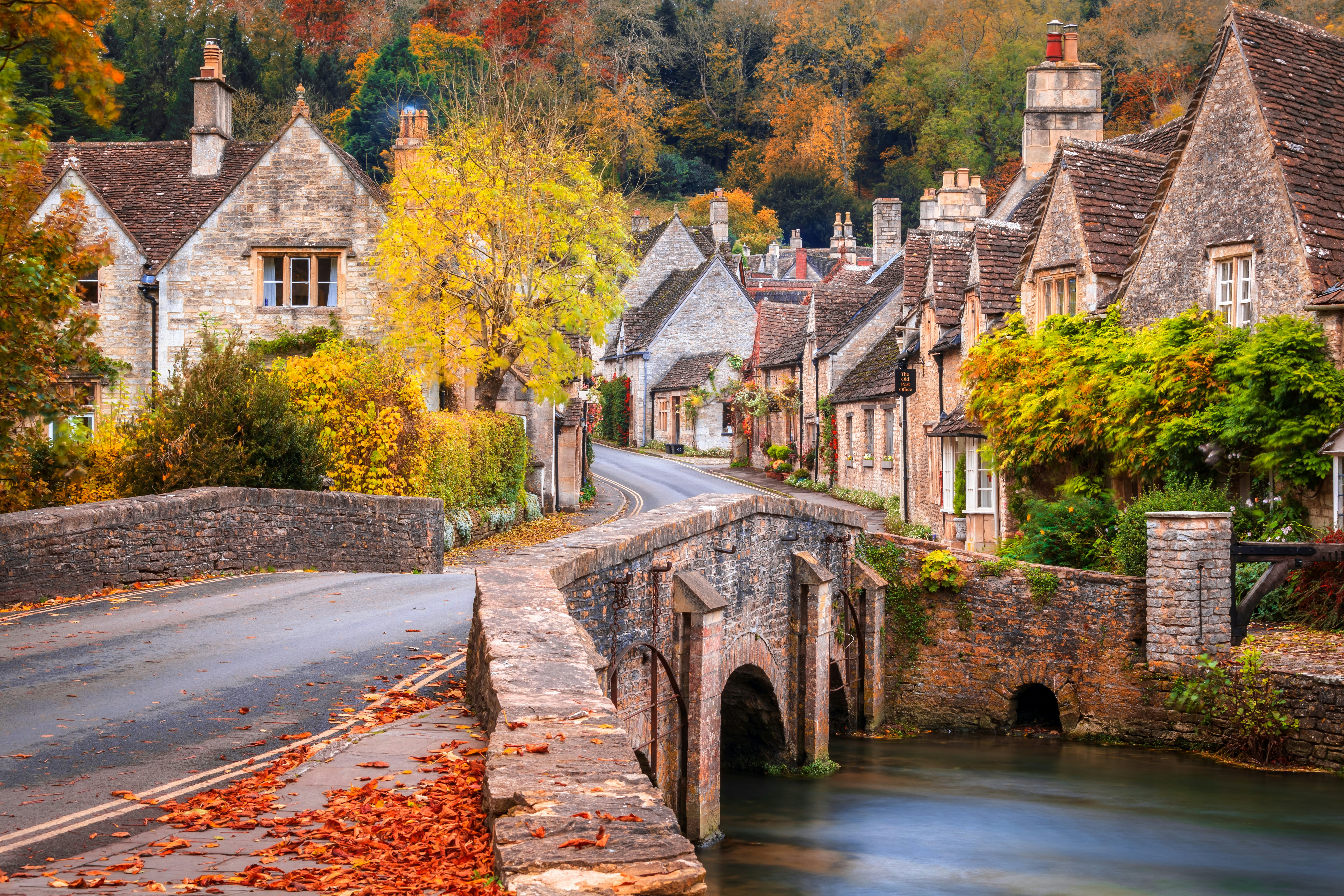 A stone bridge over Bybrook River in Castle Combe in autumn.