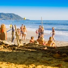 Santa Teresa, Costa Rica - June, 28, 2018: Tourists sitting in the sand and enjoying the beautiful view of Santa Teresa beach, and some surfers check out the conditions to surf License Type: media Download Time: 2023-04-05T01:12:47.000Z User: mvm_lonelyplanet Is Editorial: Yes purchase_order: