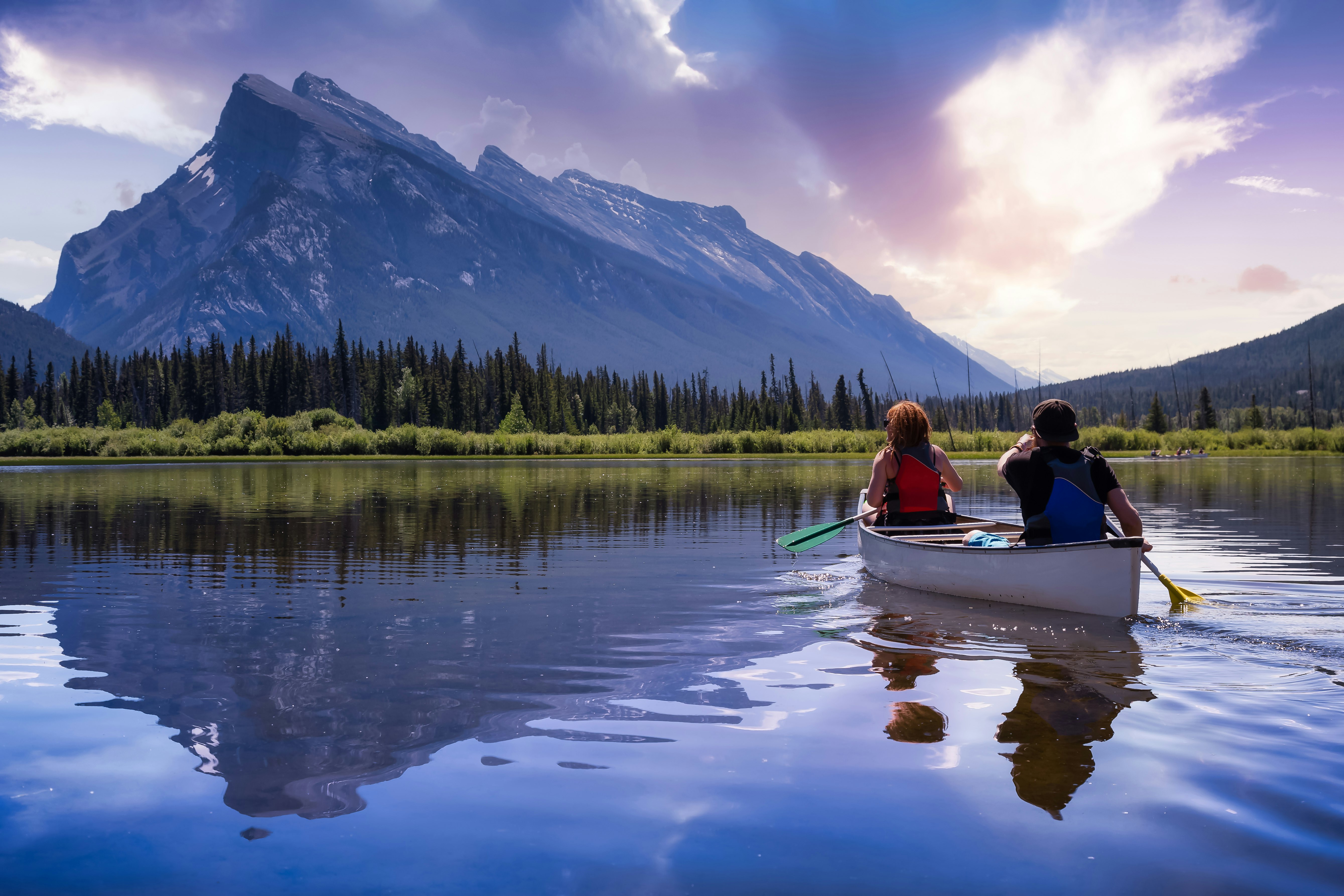 Two people in a small rowboat head out onto an alpine lake